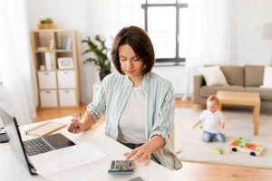 work from home mother counting on calculator and baby